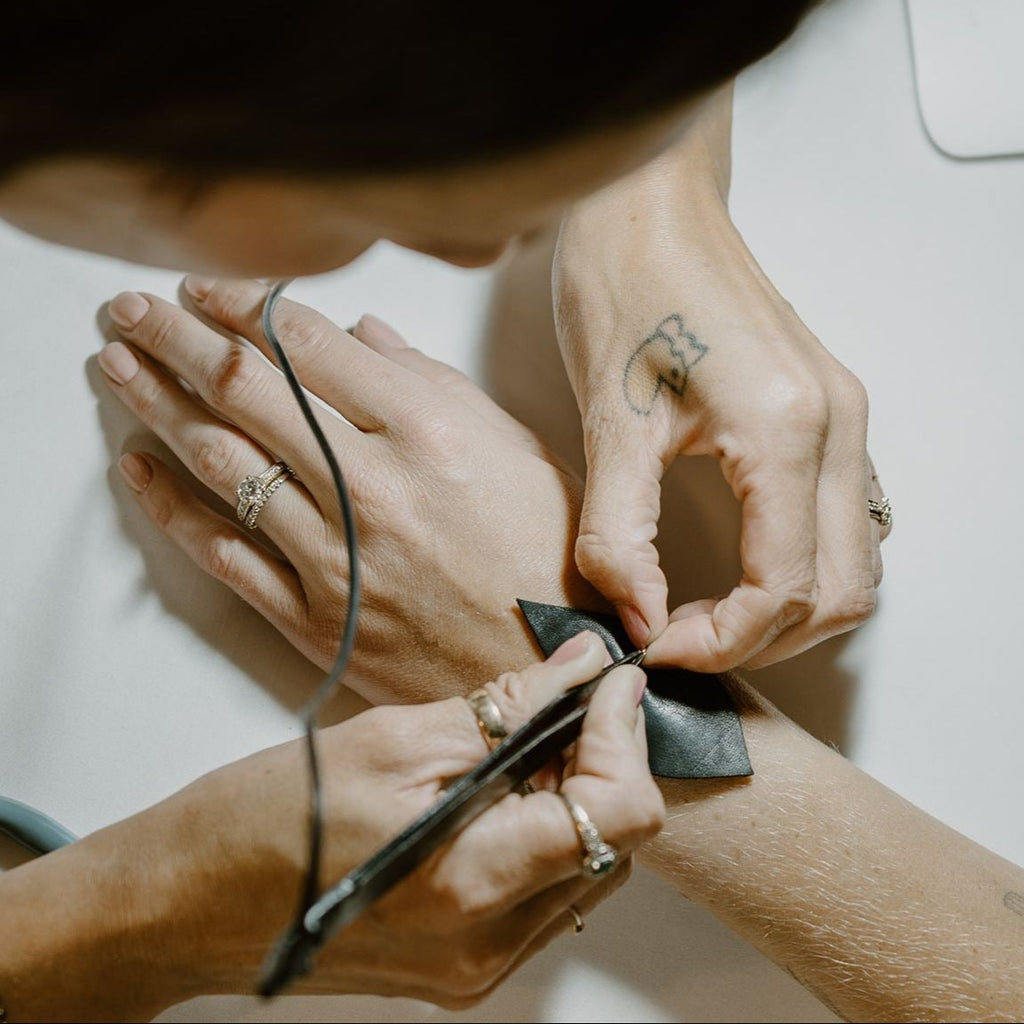 Close-up of hands tying a bow with a focus on jewelry.