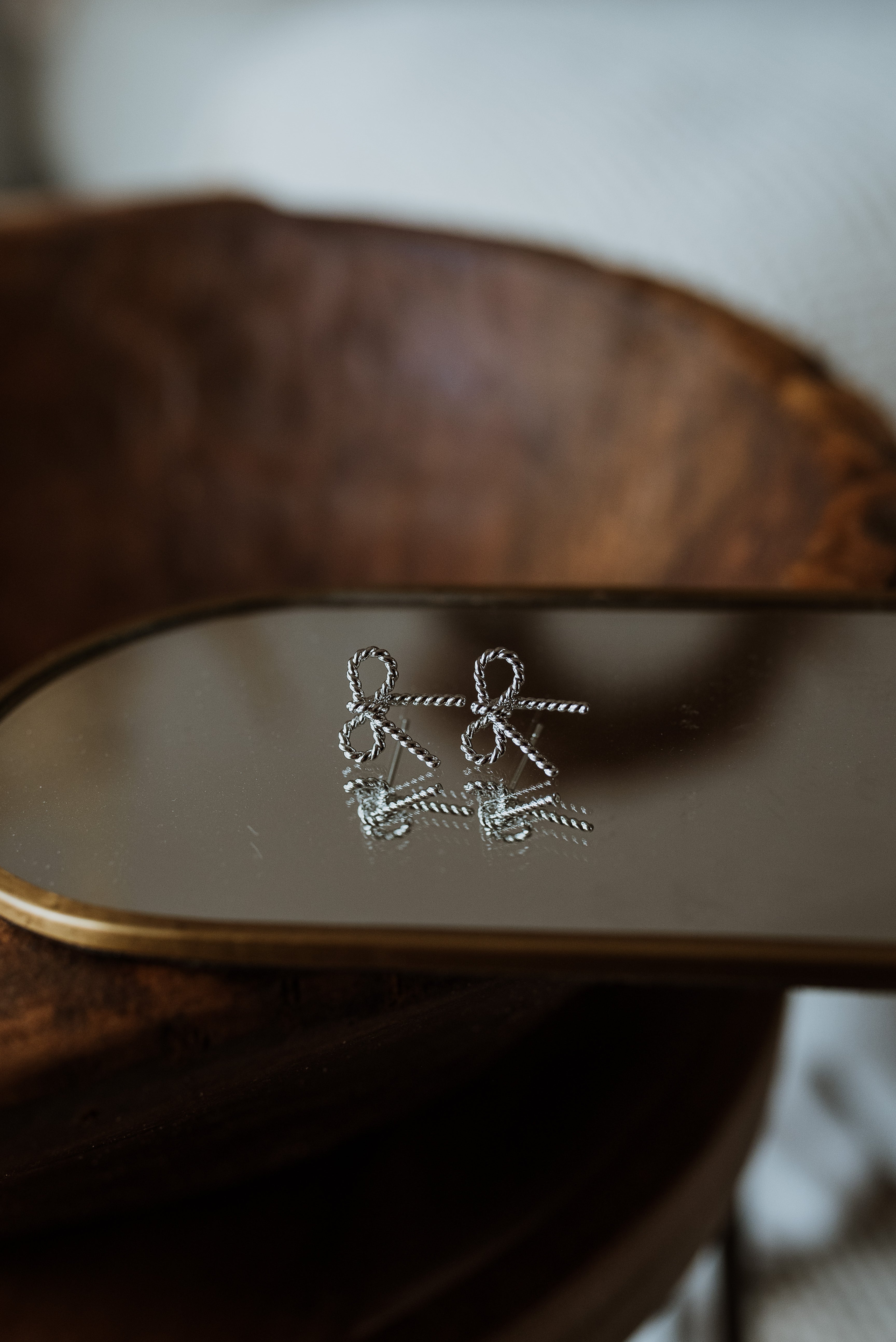 Silver earrings on a wooden surface with a blurred background