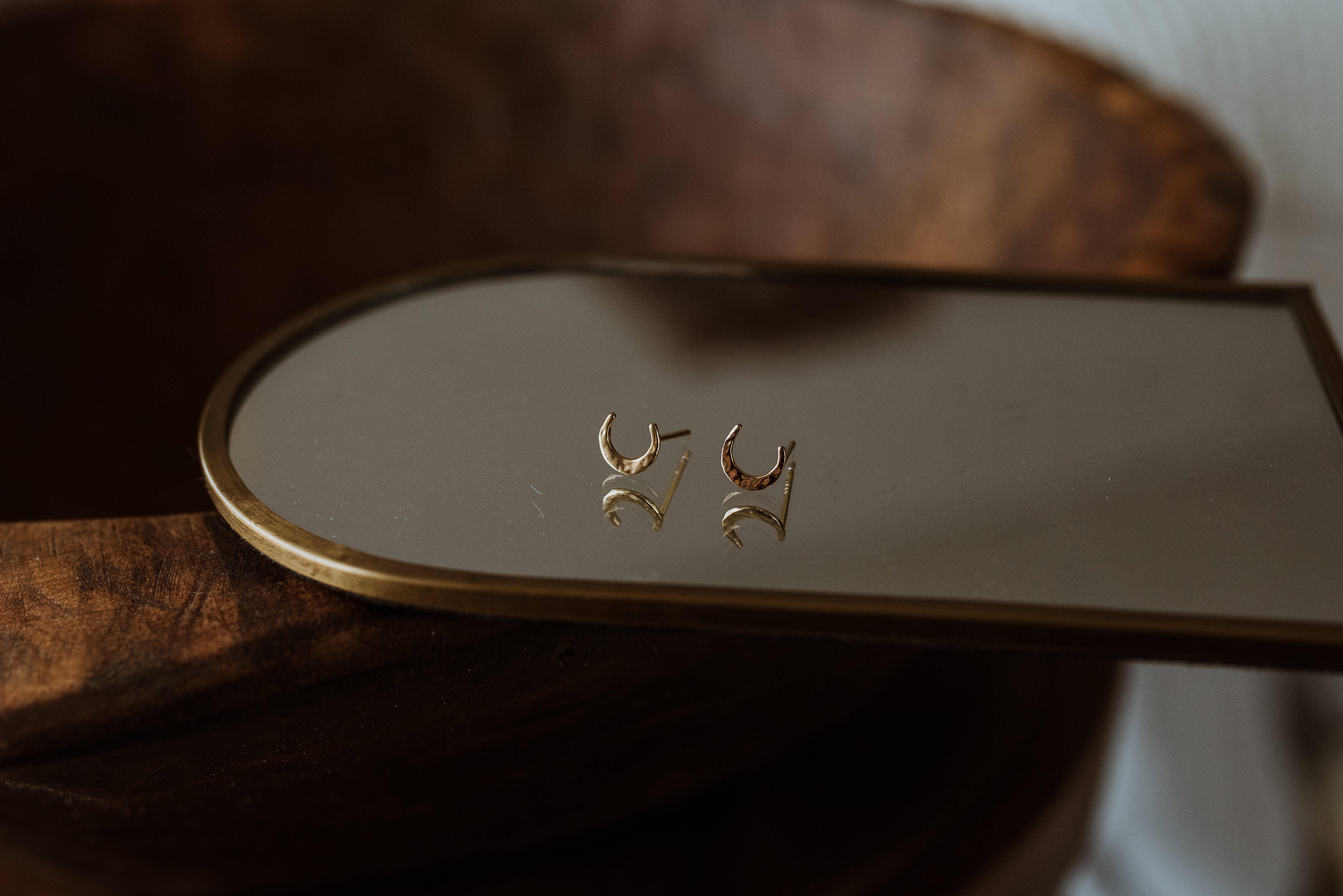 Gold earrings on a mirror with a blurred background
