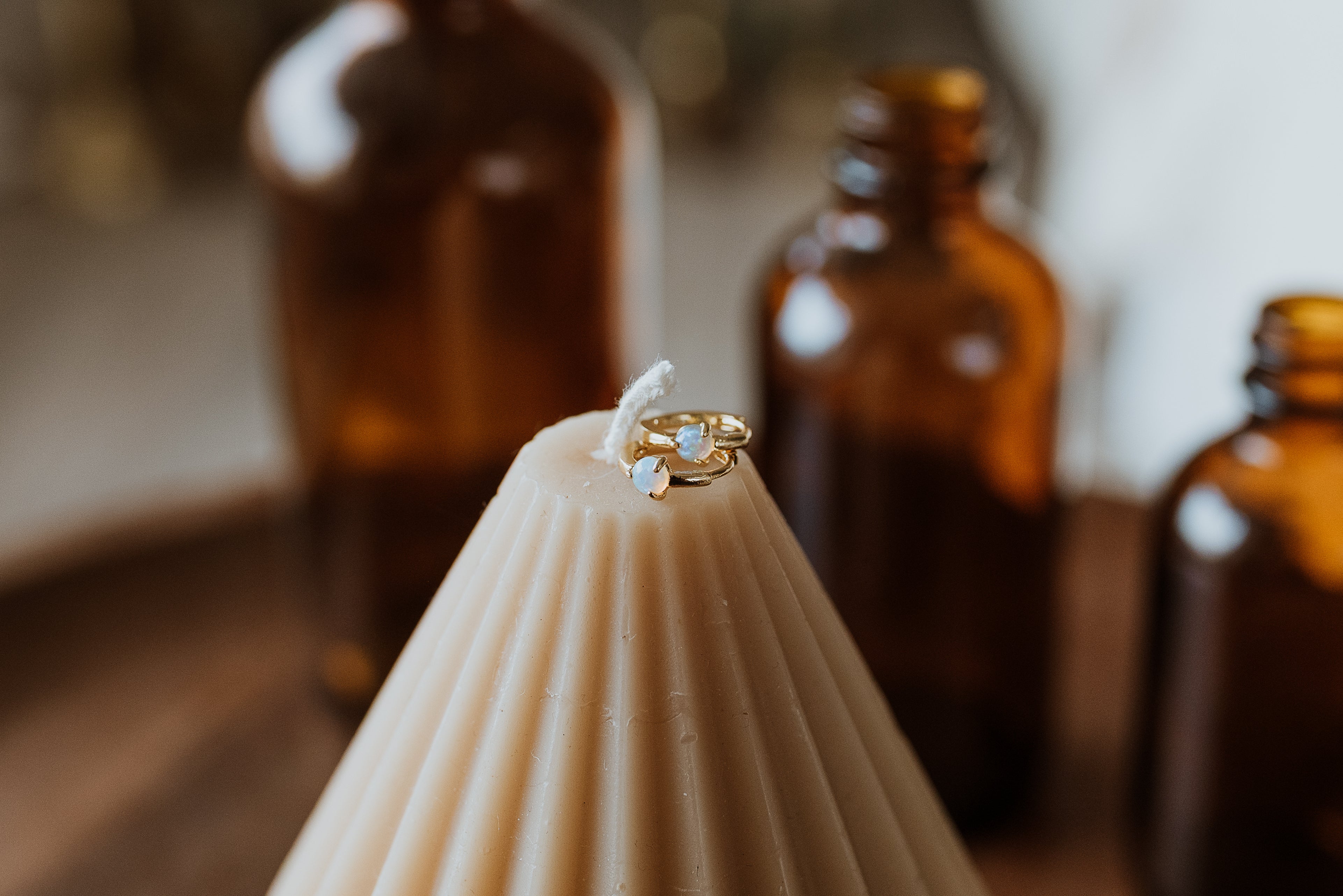 Earrings on a candle with blurred brown bottles in the background