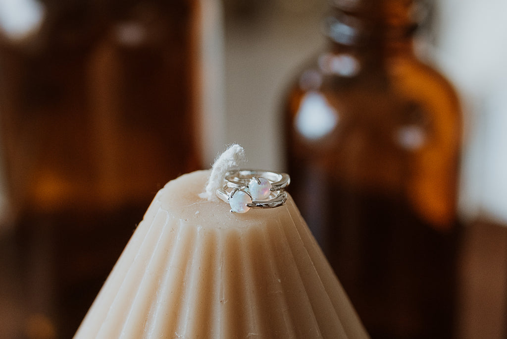 Silver earrings with opal stones on a white candle against a blurred background