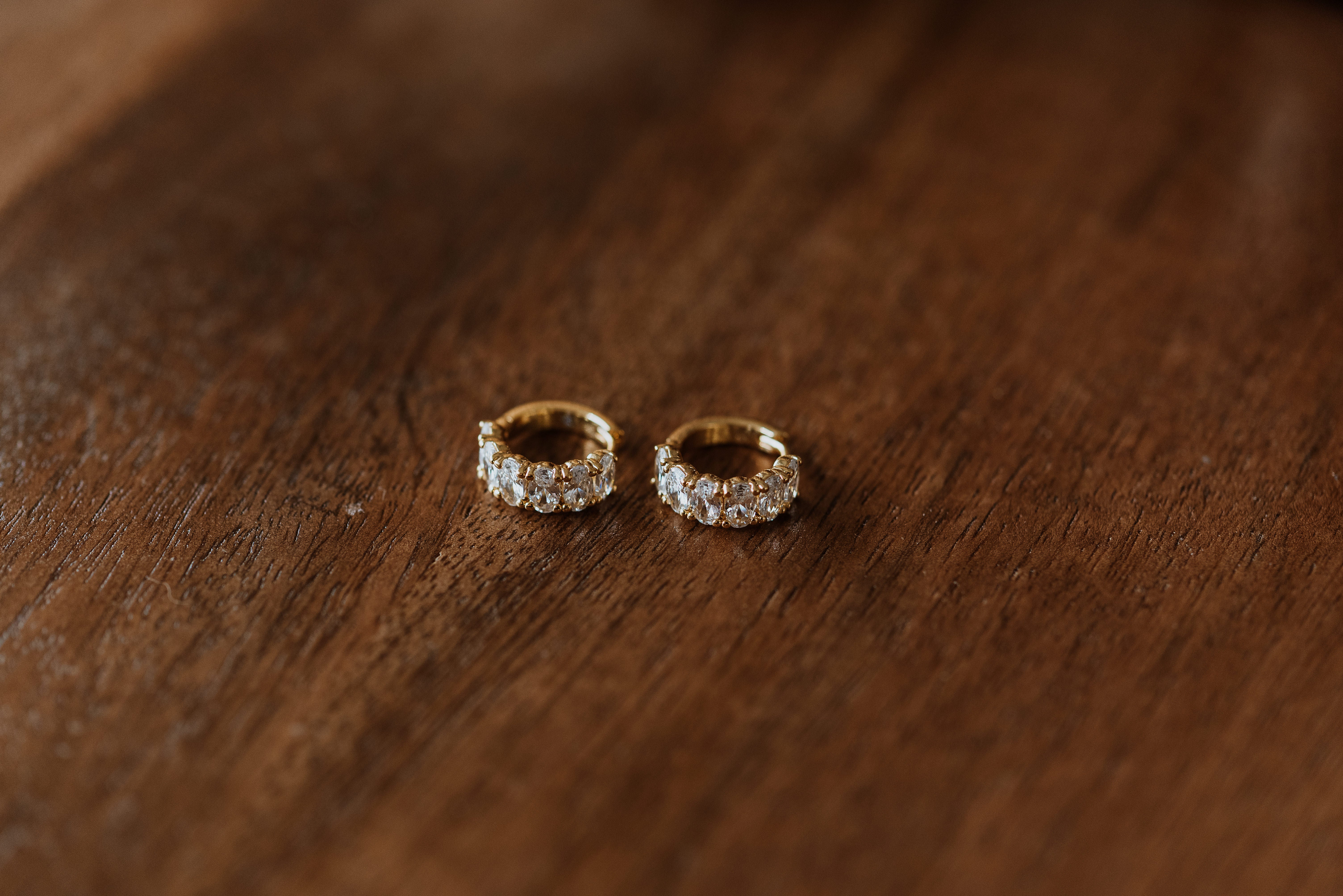 Pair of gold hoop earrings with embedded stones on a wooden surface