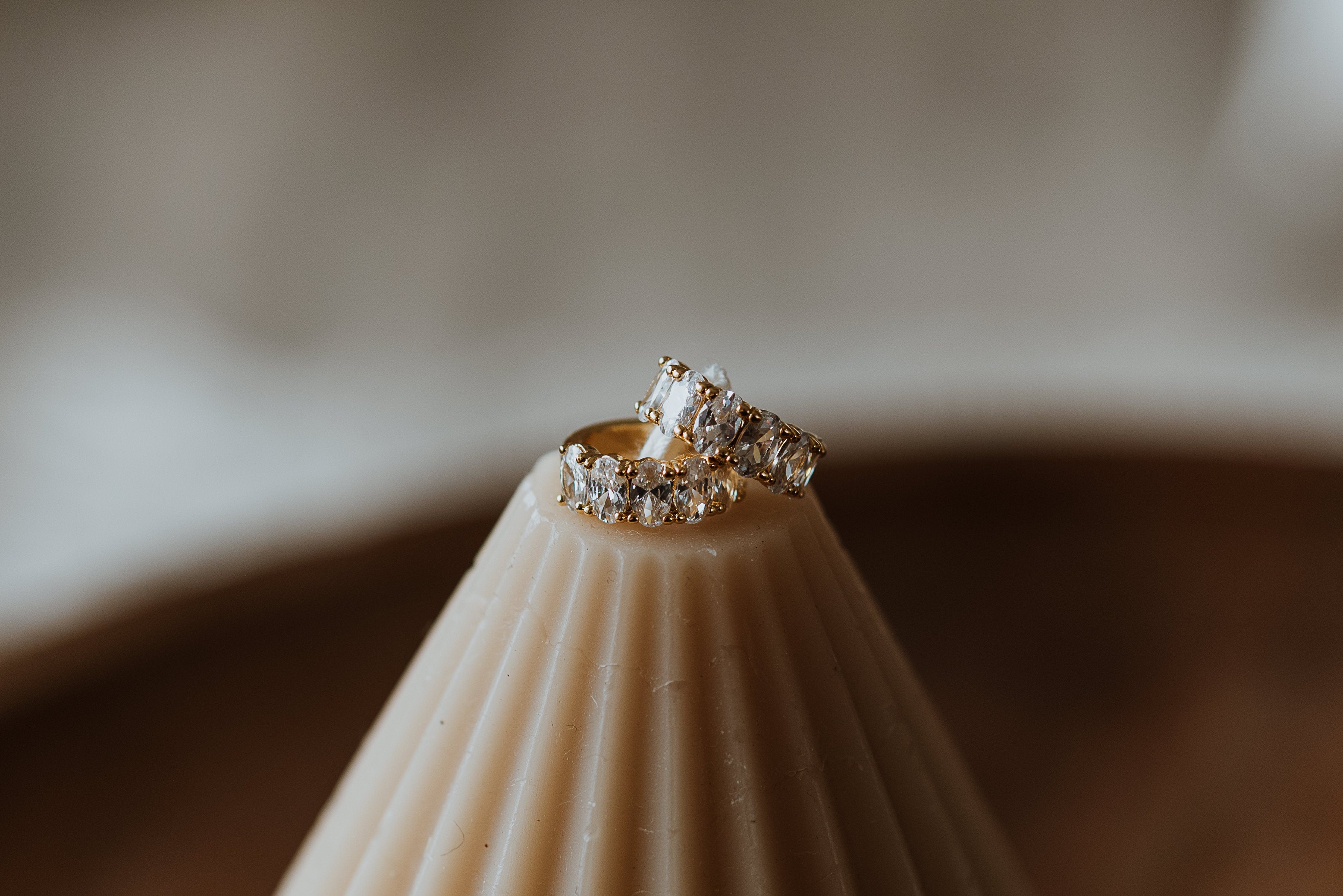 Gold earrings on a candle stand against a blurred background
