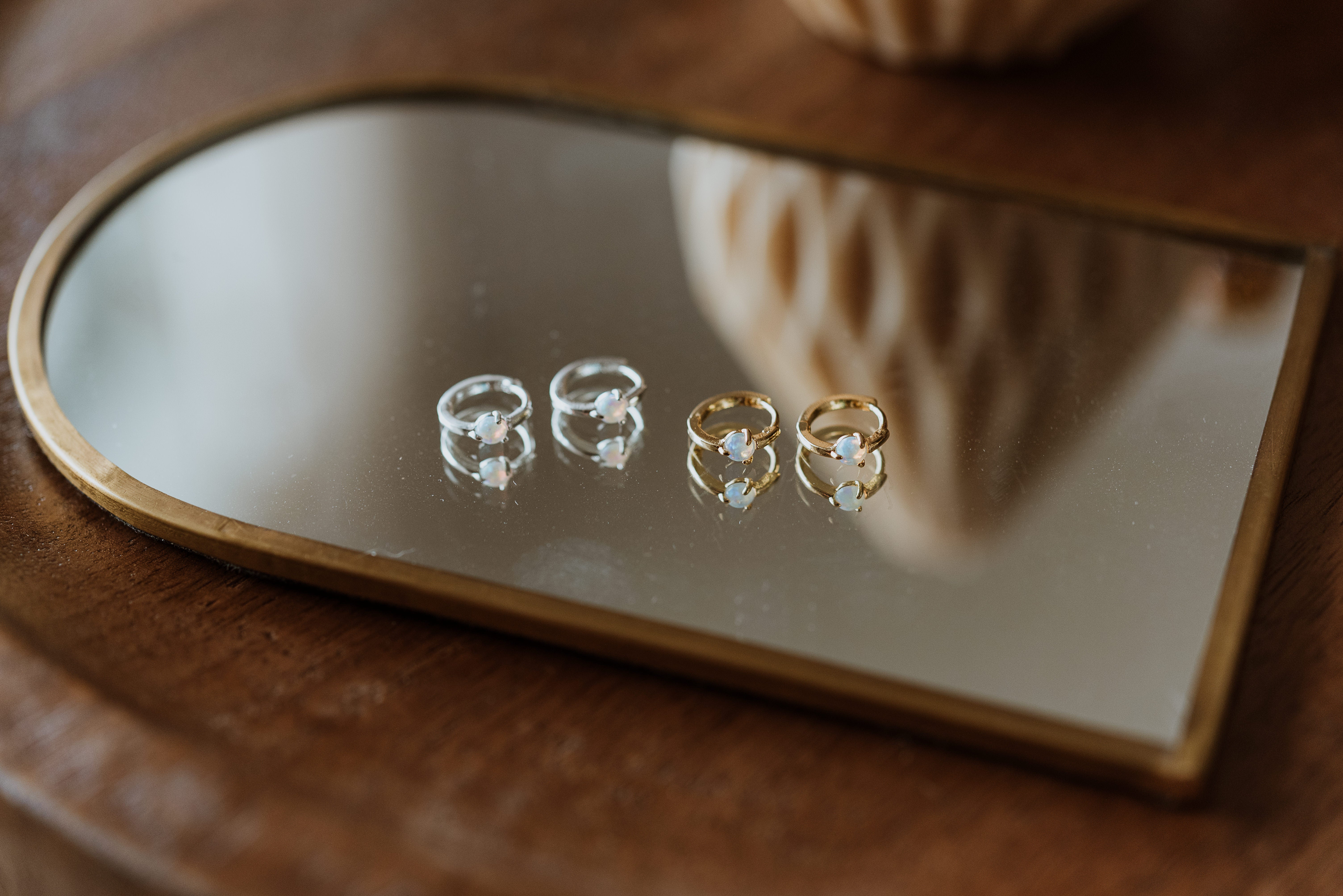 Set of earrings on a reflective surface with a wooden background