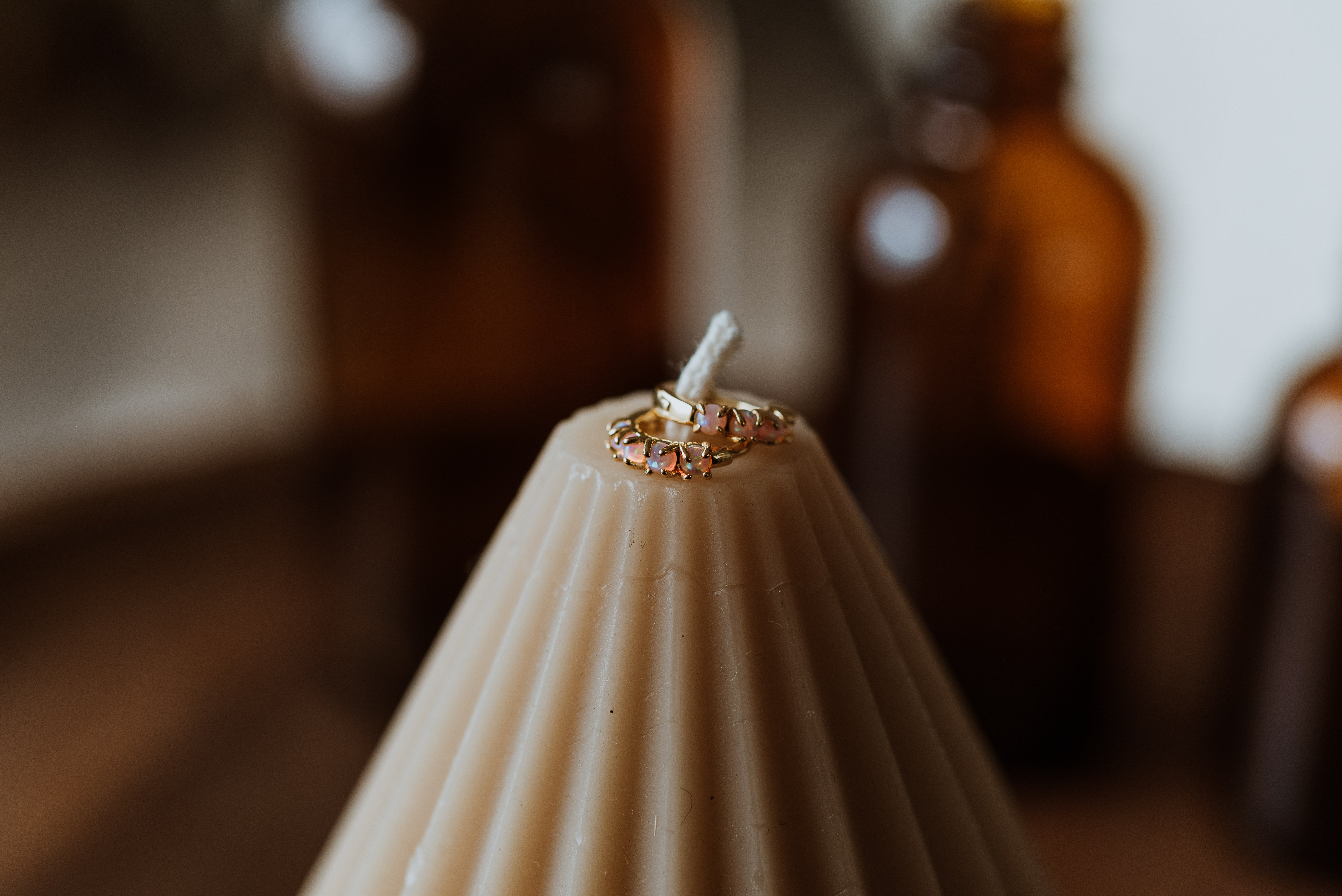 Beige candle with a decorative earrings on top, blurred background