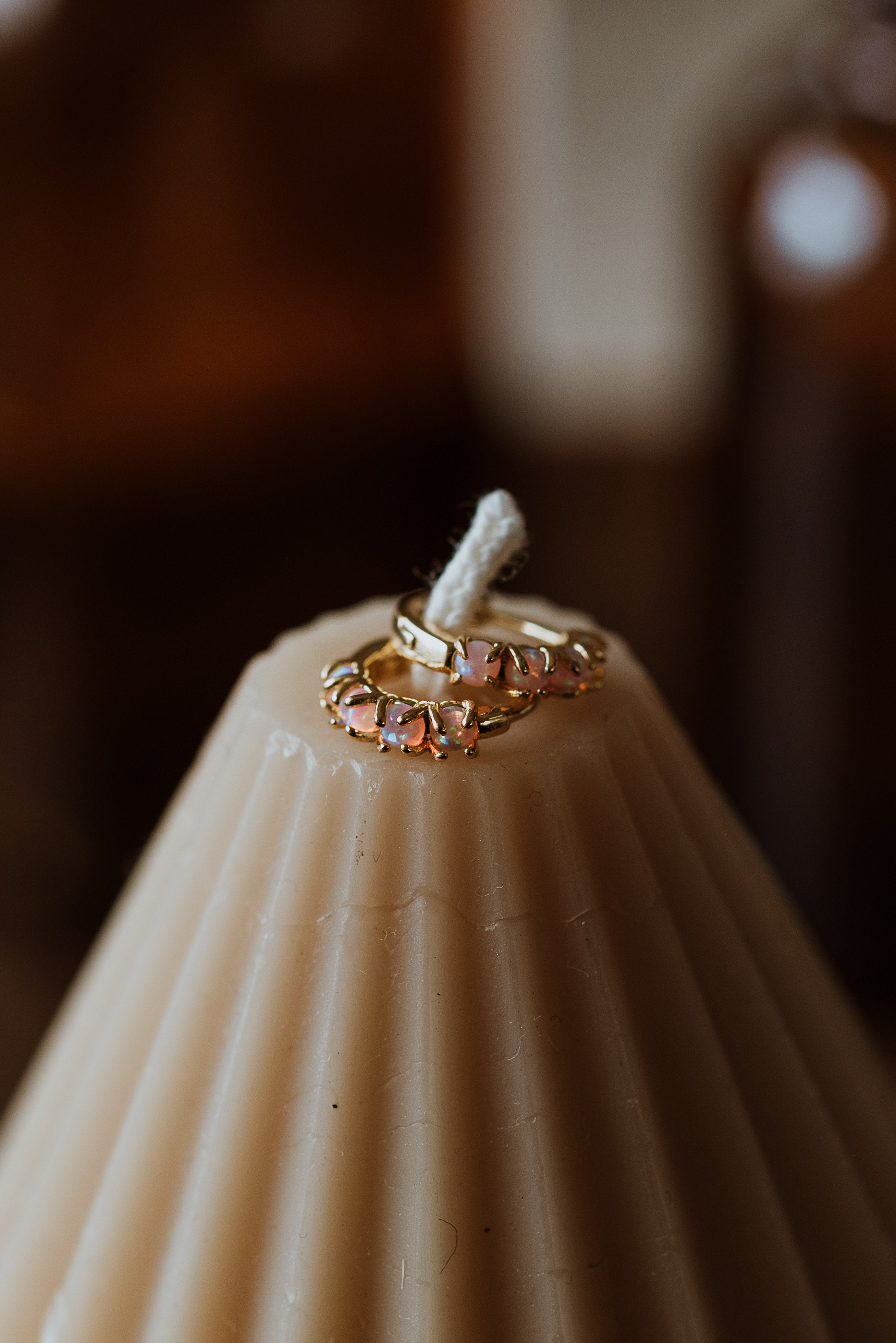 Gold earrings on a textured candle surface with a blurred background