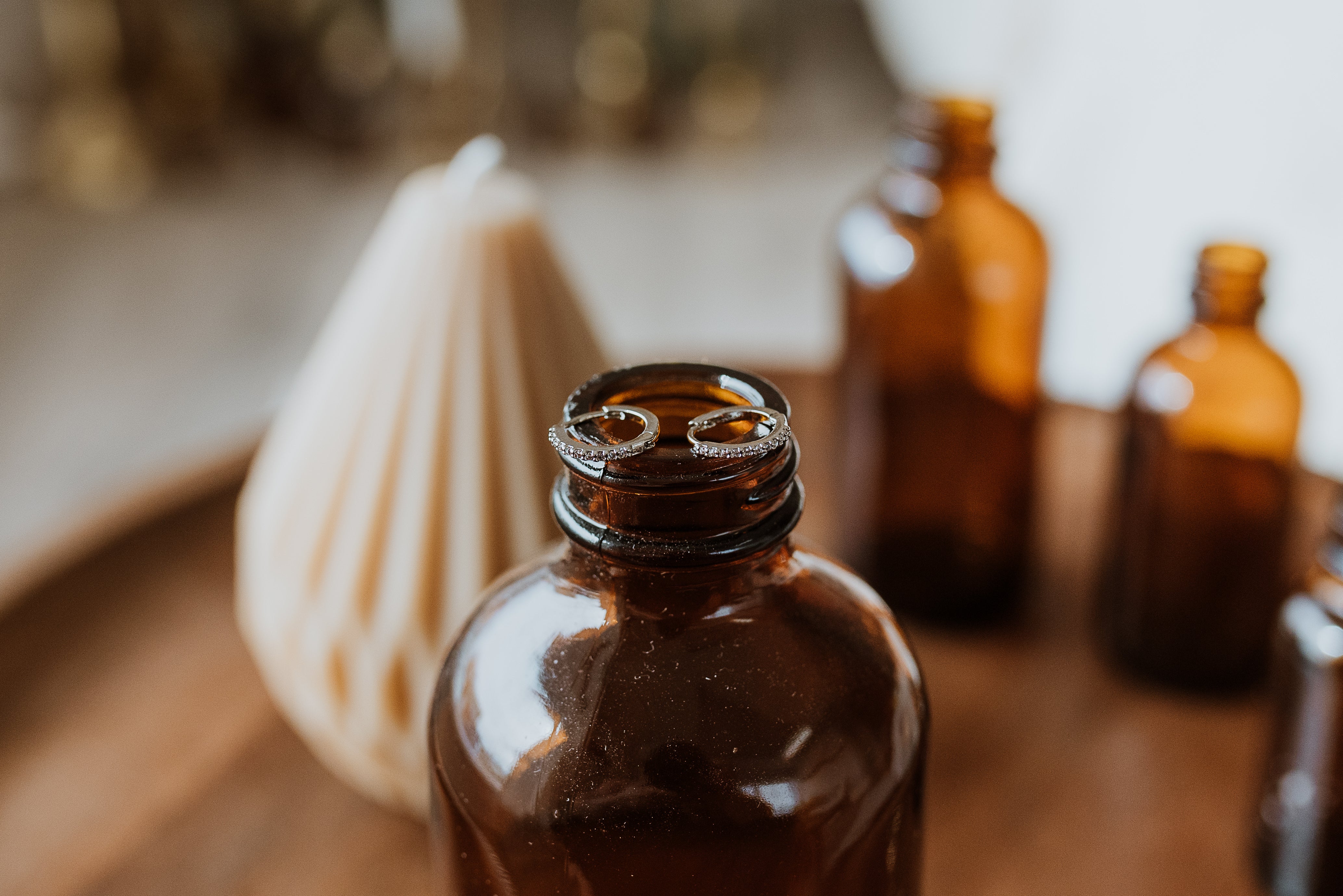 Brown glass bottles on a wooden surface with a blurred background showcasing silver earrings