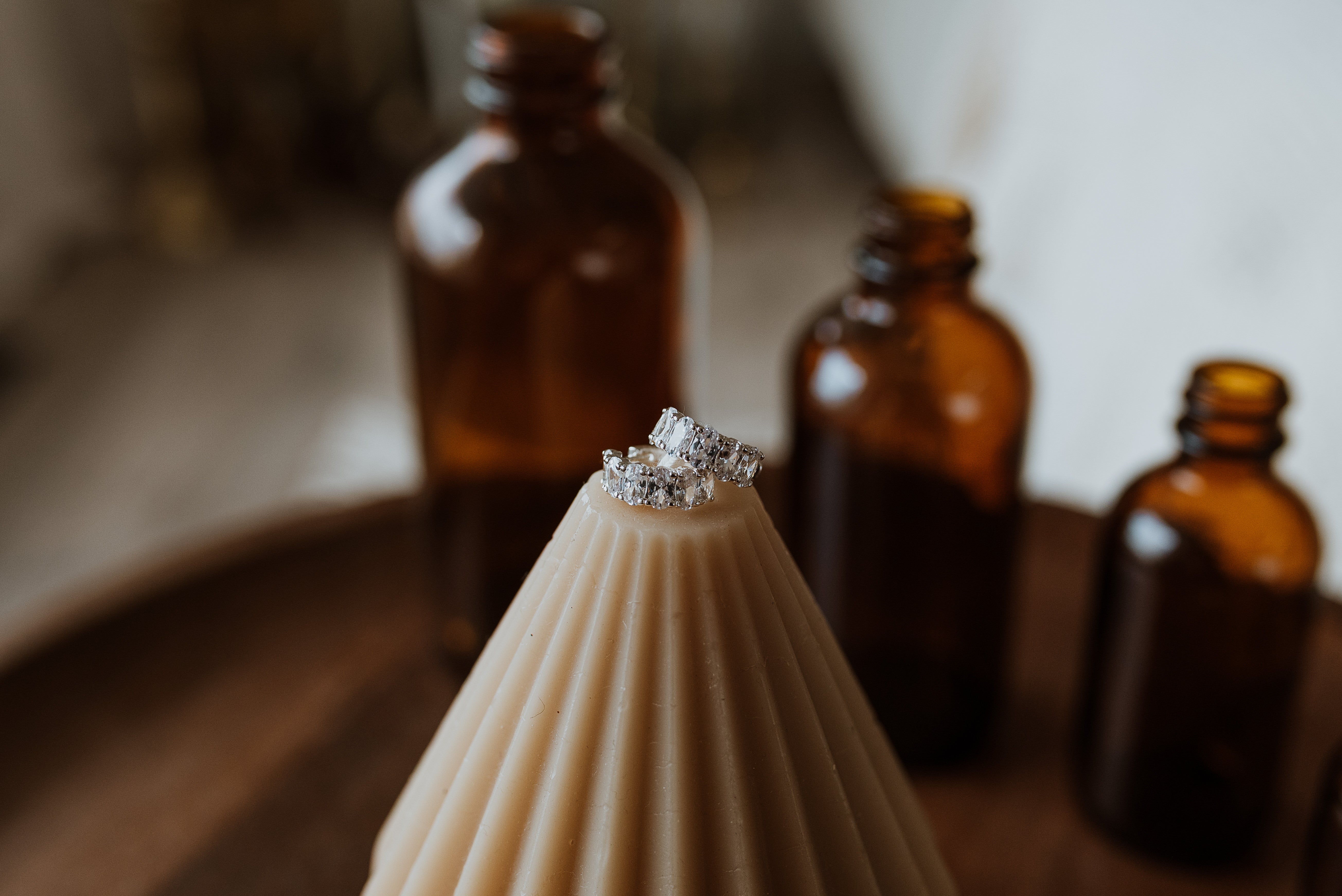 Decorative item with silver earrings on top, surrounded by amber glass bottles.