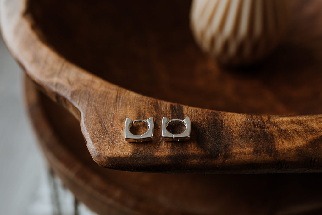 Silver square earrings on a wooden surface