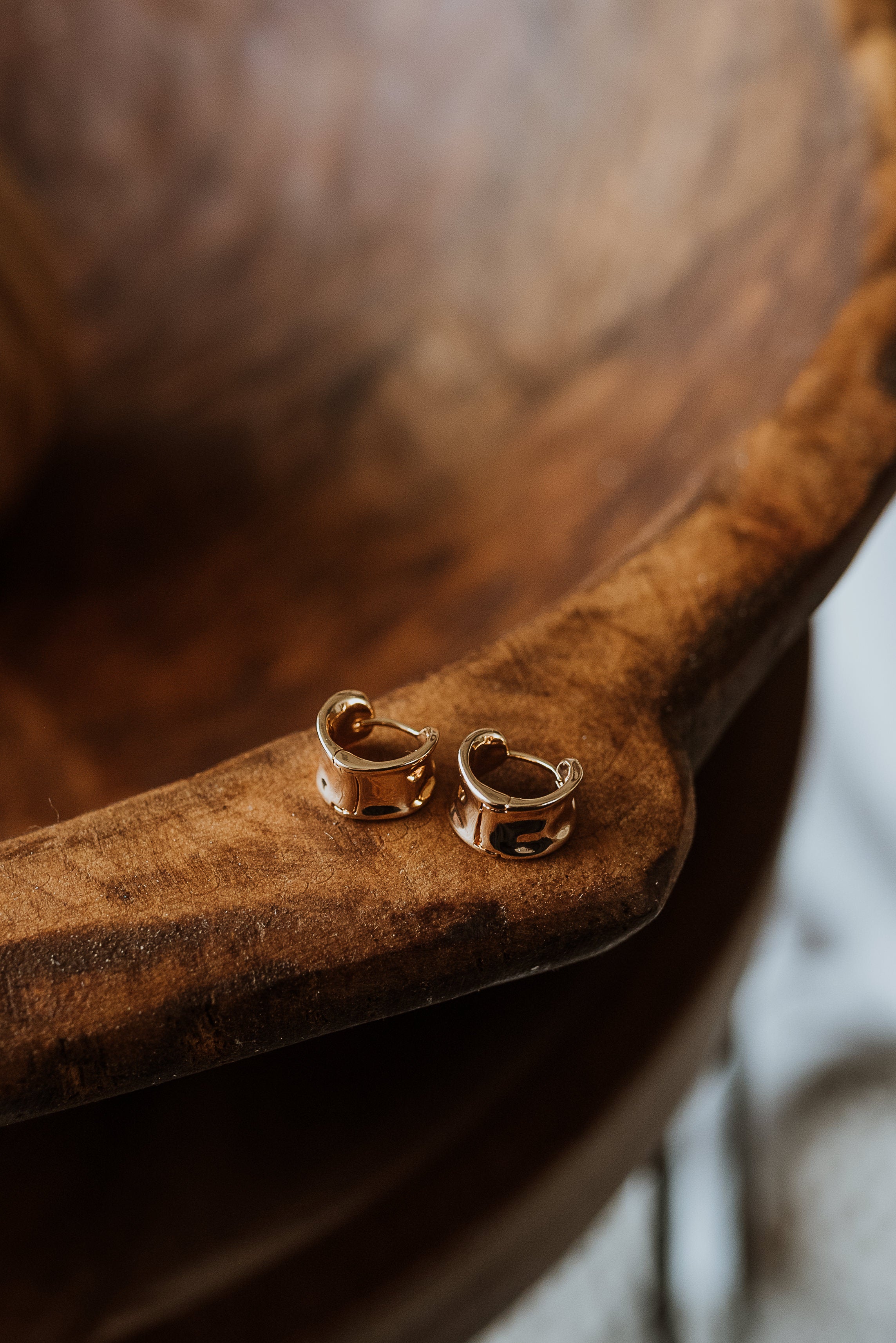Gold hoop earrings on a wooden surface