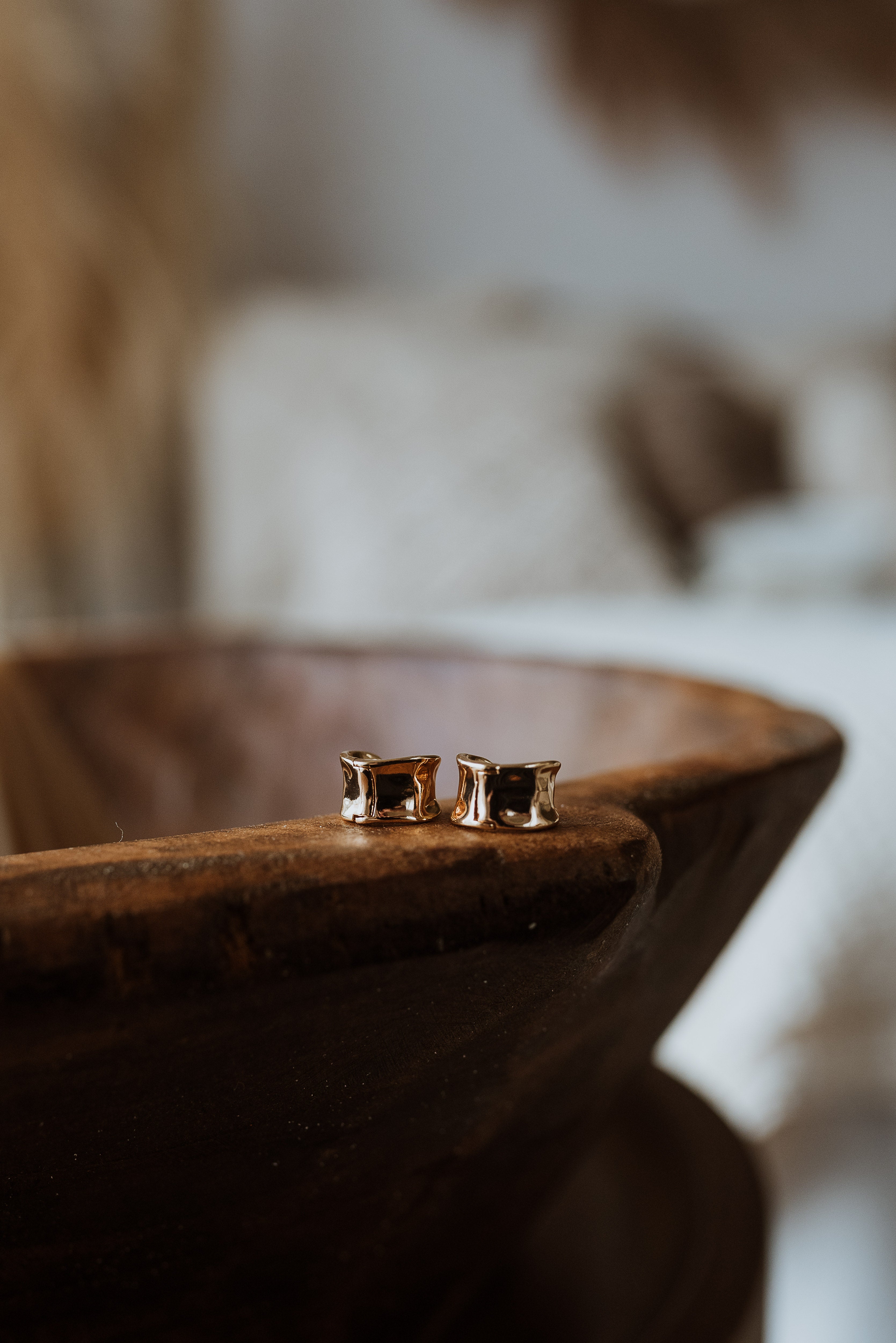 Gold earrings on a wooden surface with a blurred background