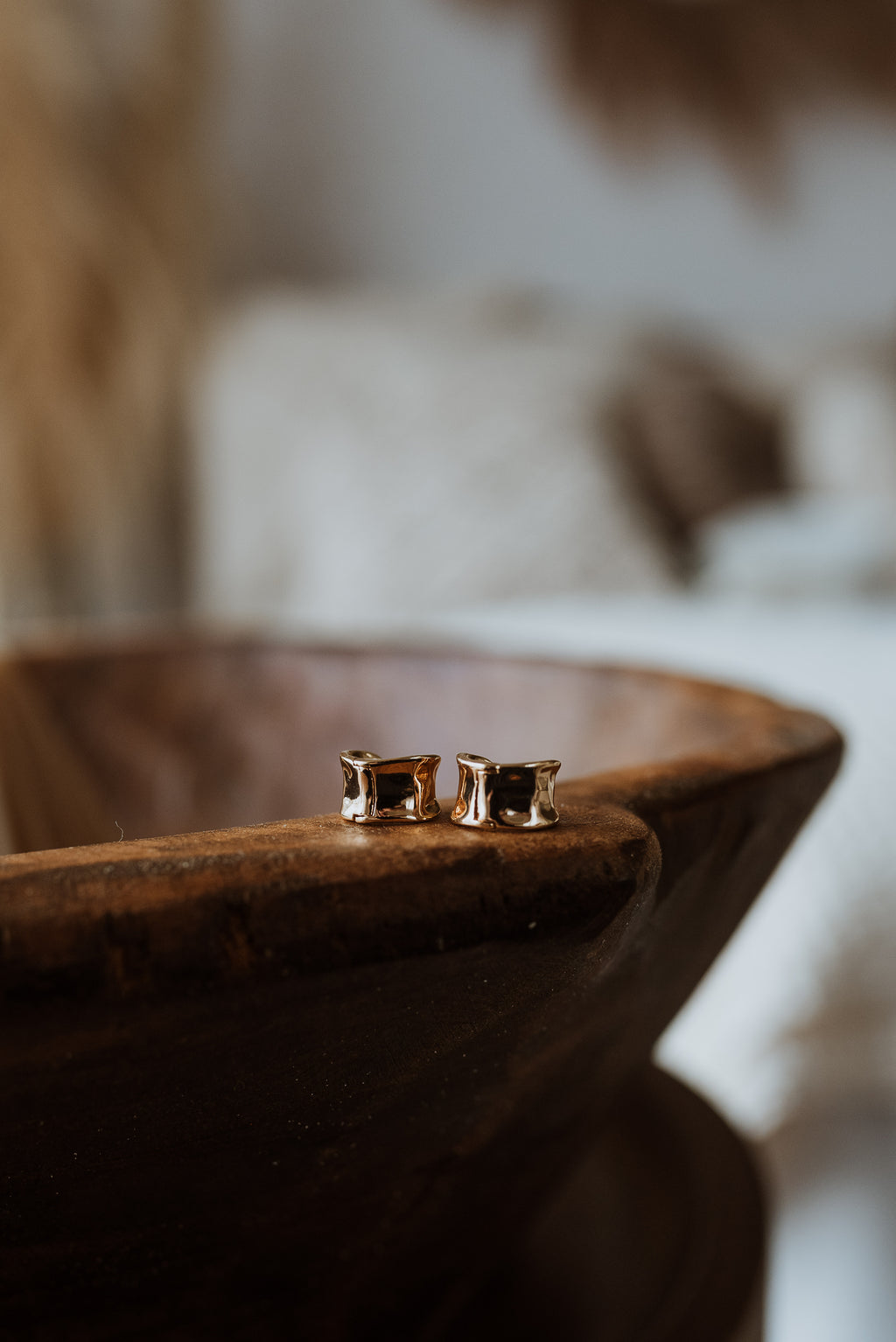 Gold earrings on a wooden surface with a blurred background