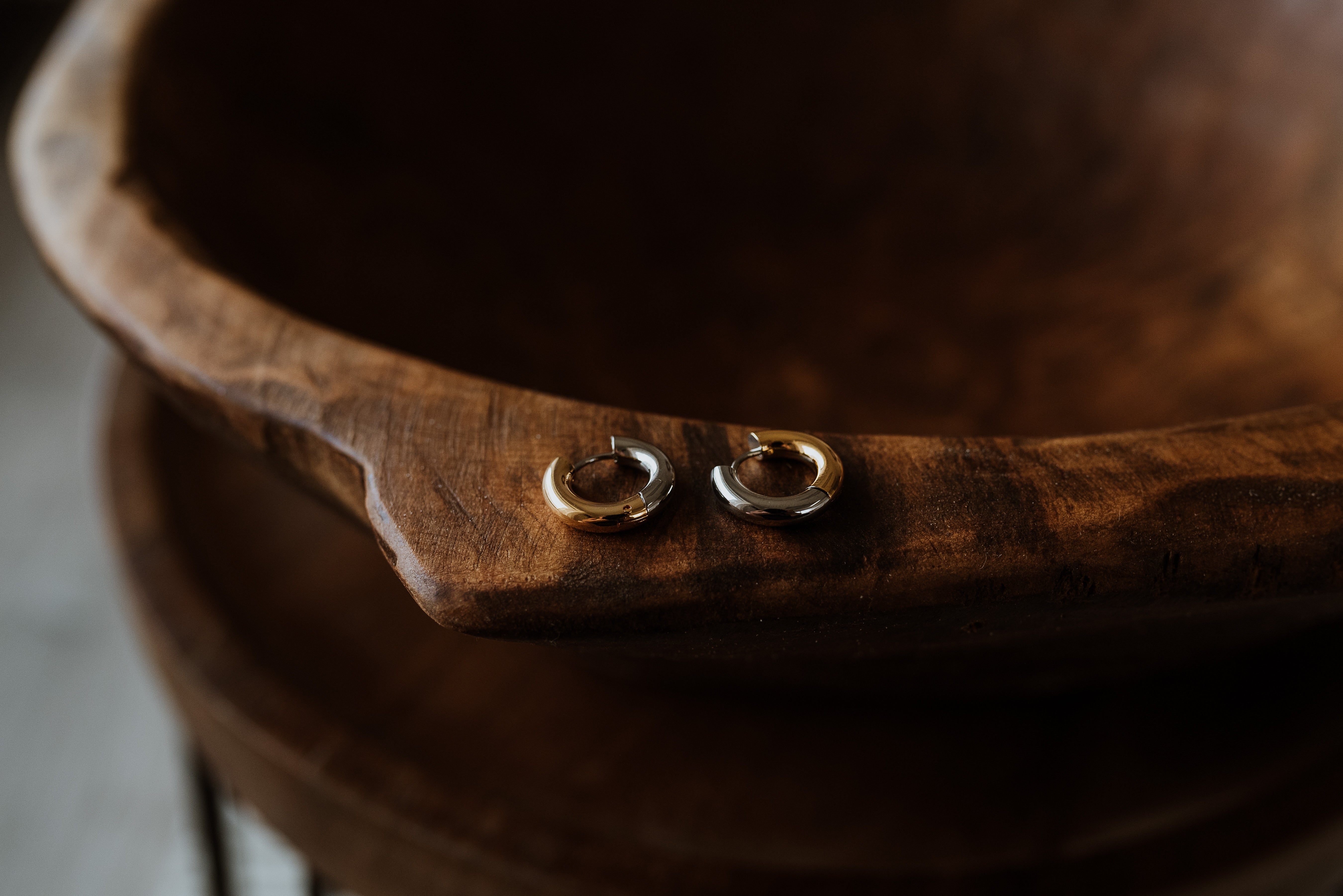 Close-up of a wooden bowl with earrings on a blurred background