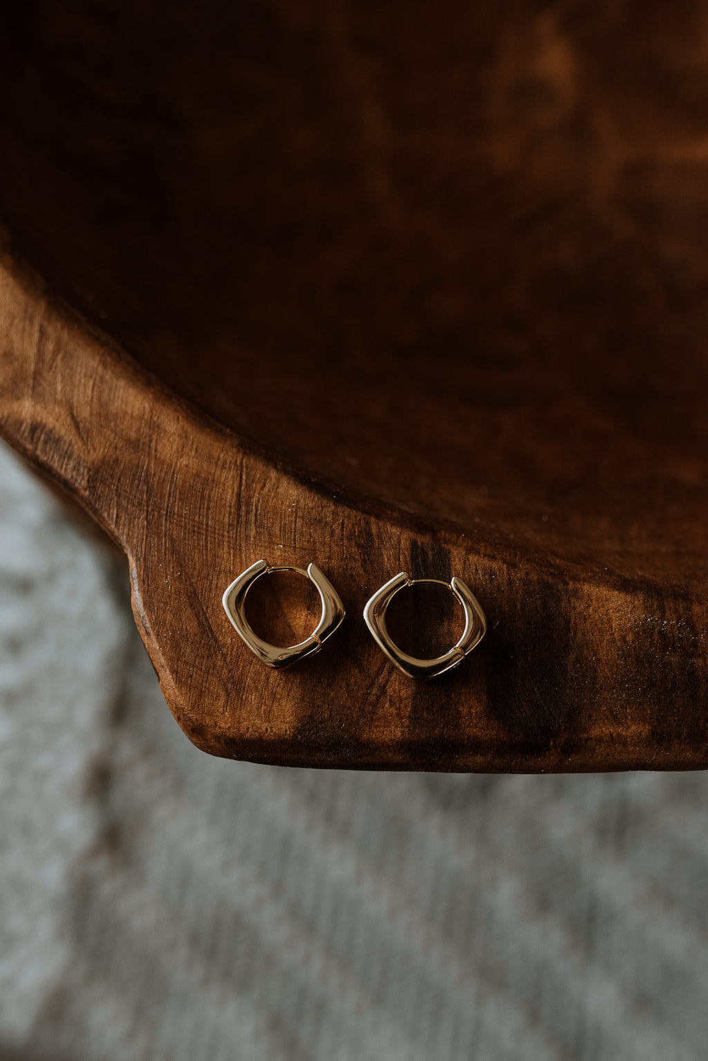 Gold hoop earrings on a wooden surface