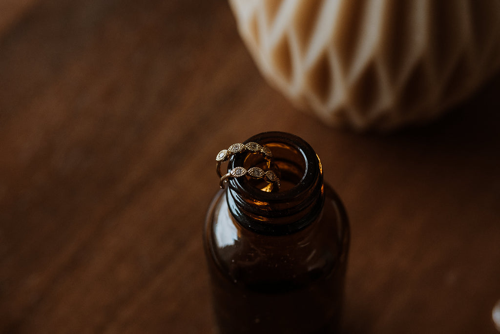 Brown glass bottle with hoop earrings on a wooden surface