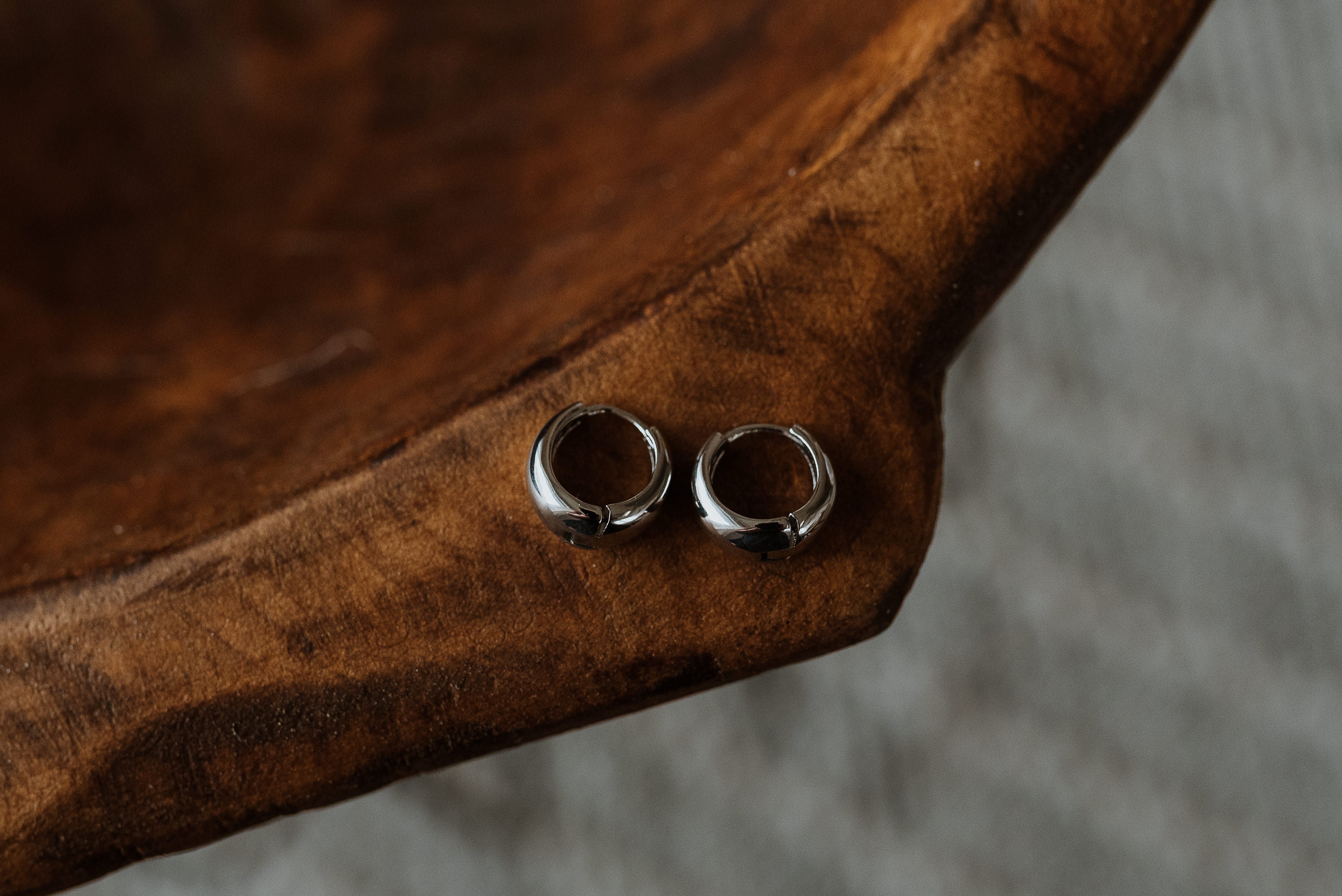 Two silver hoop earrings on a wooden surface
