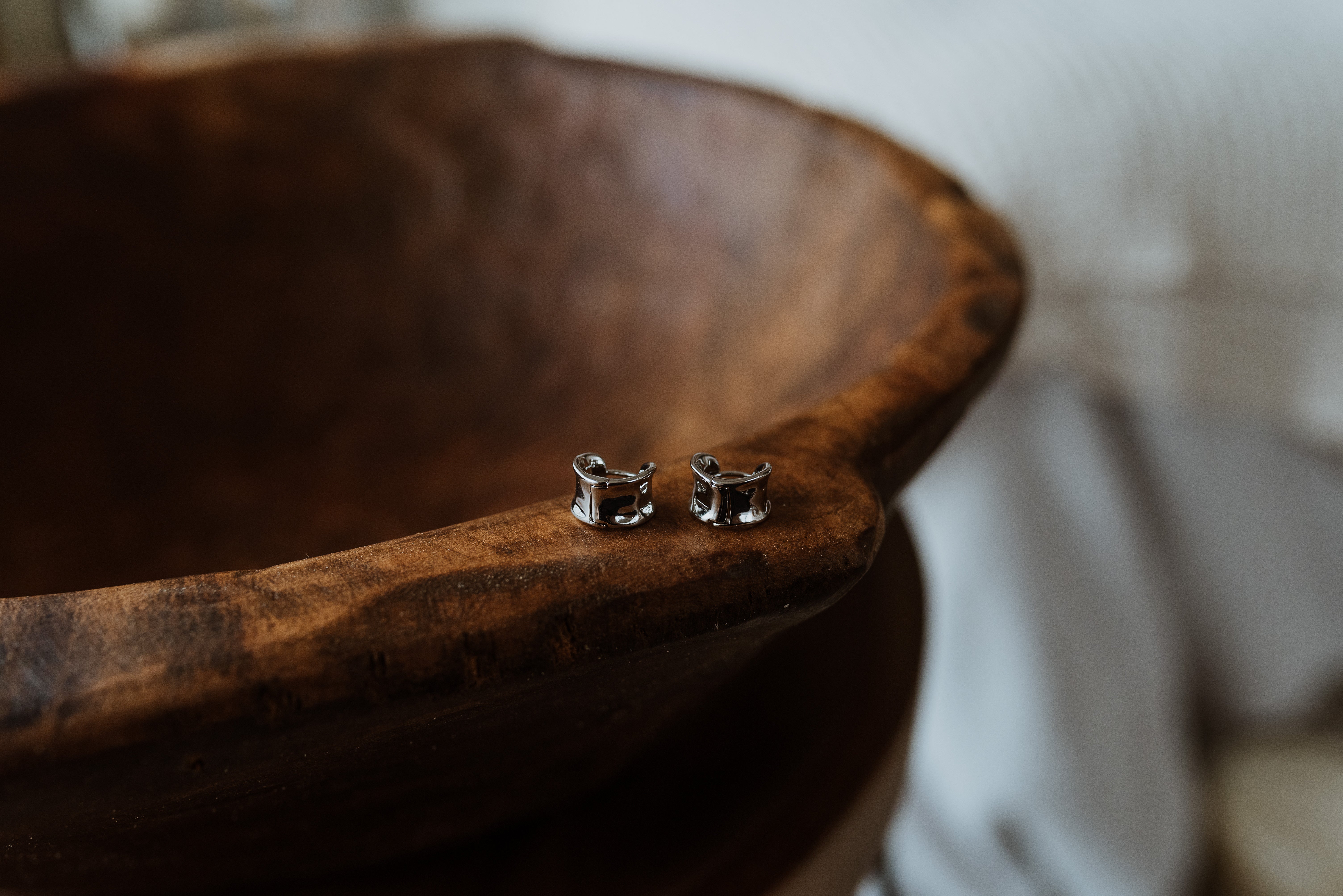 Pair of silver square earrings on a wooden surface
