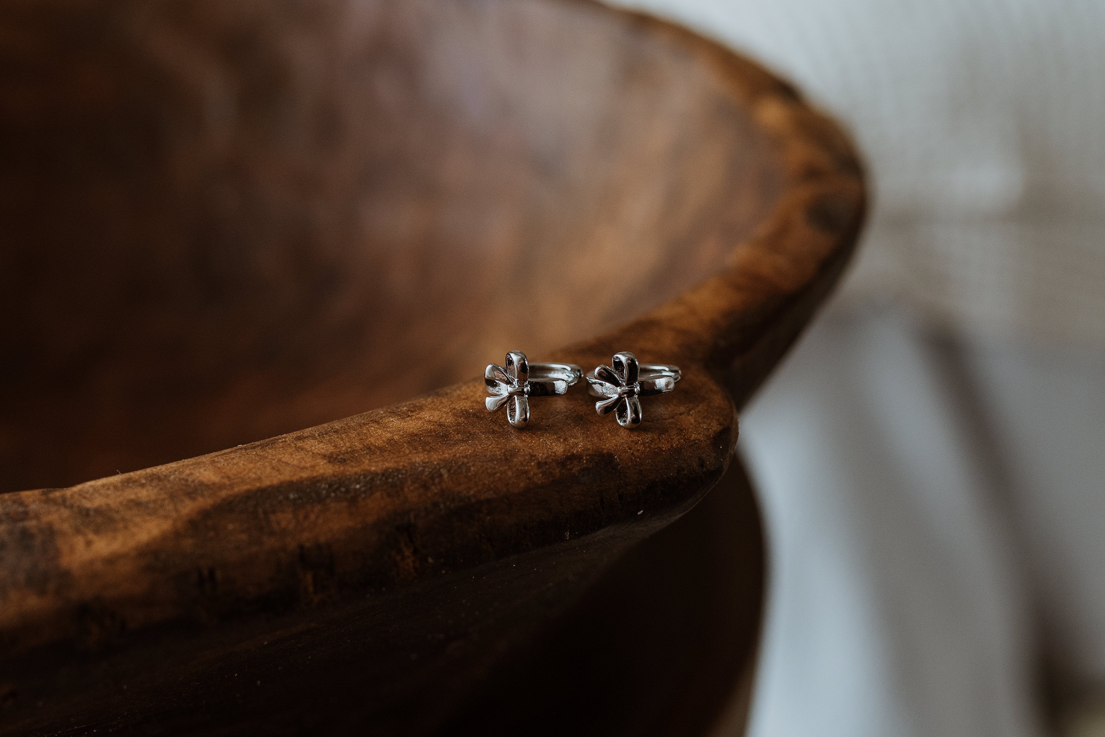 Silver bow-shaped earrings on a wooden surface
