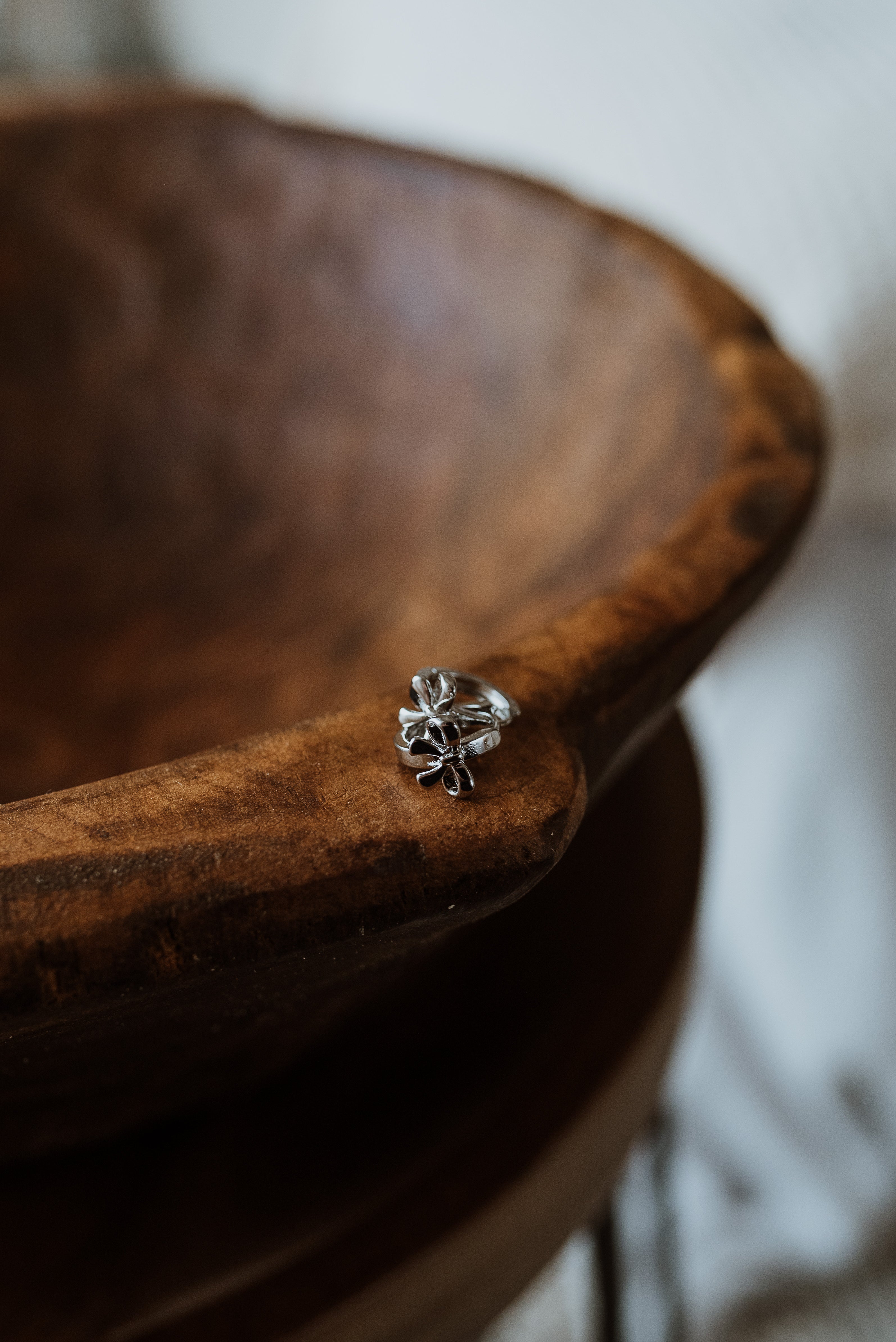 Silver earrings on a wooden surface with a blurred background