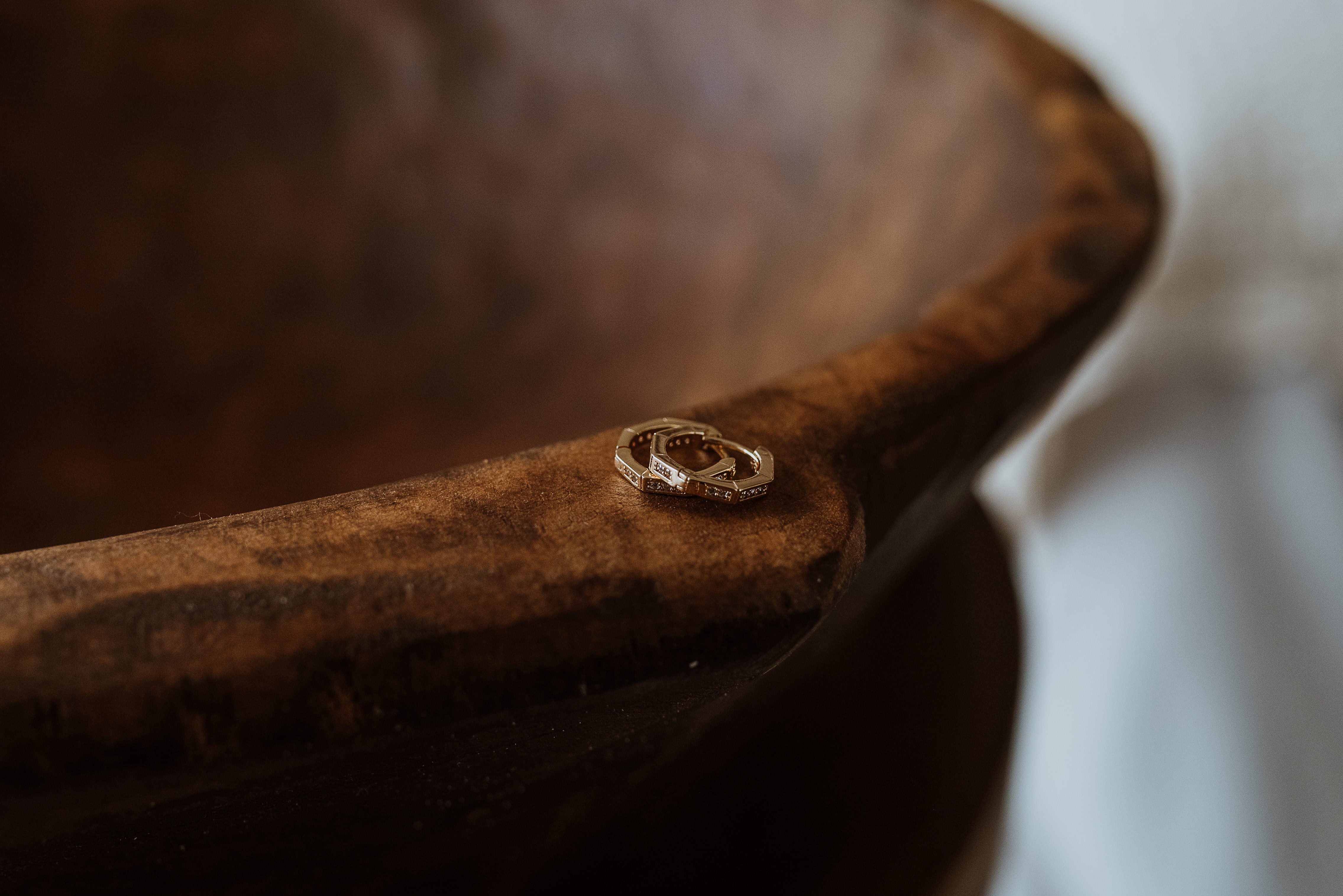 Close-up of a wooden bowl with a focus on texture and color with hexagon style gold earrings