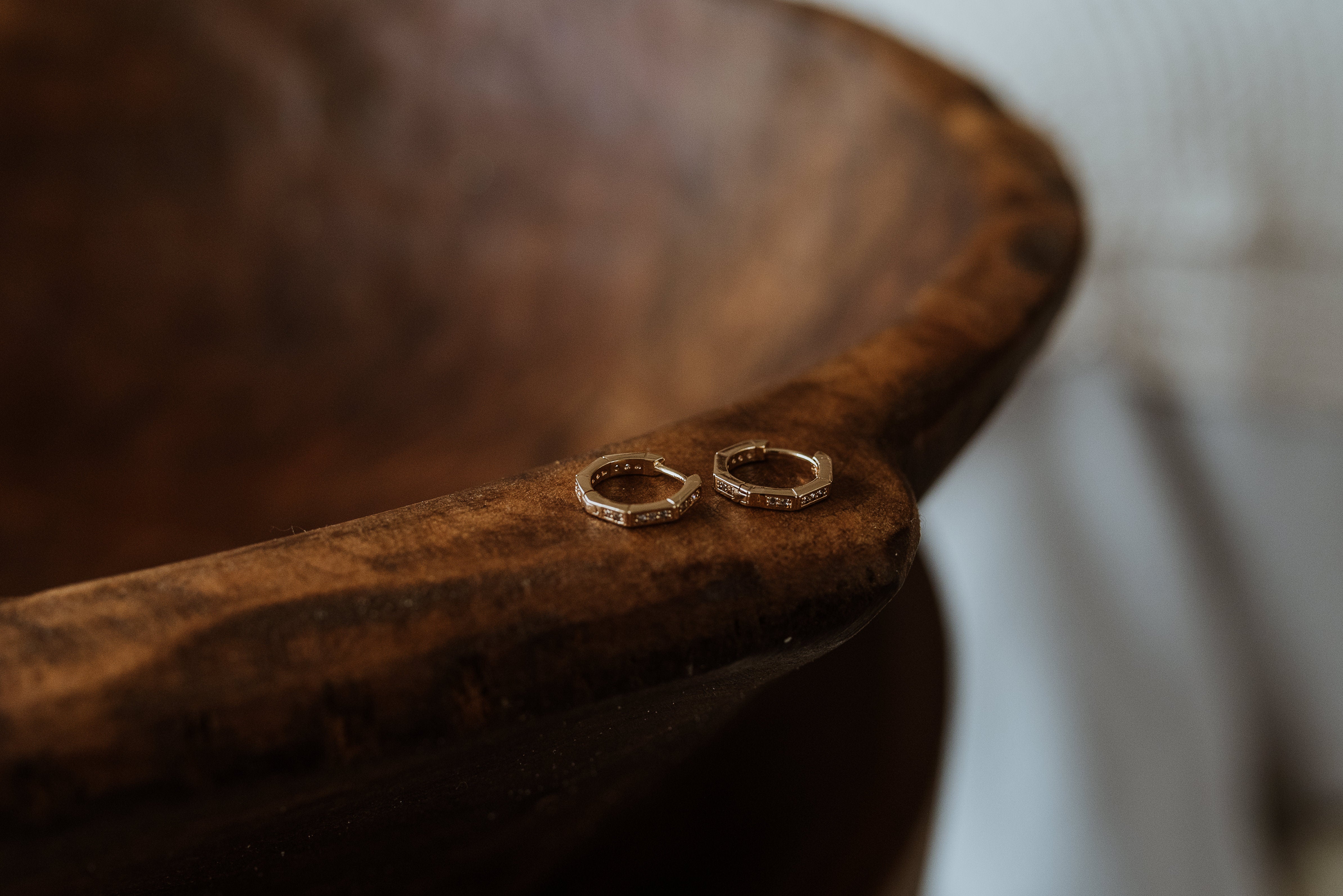 Pair of gold hexagon hoop earrings on a wooden surface