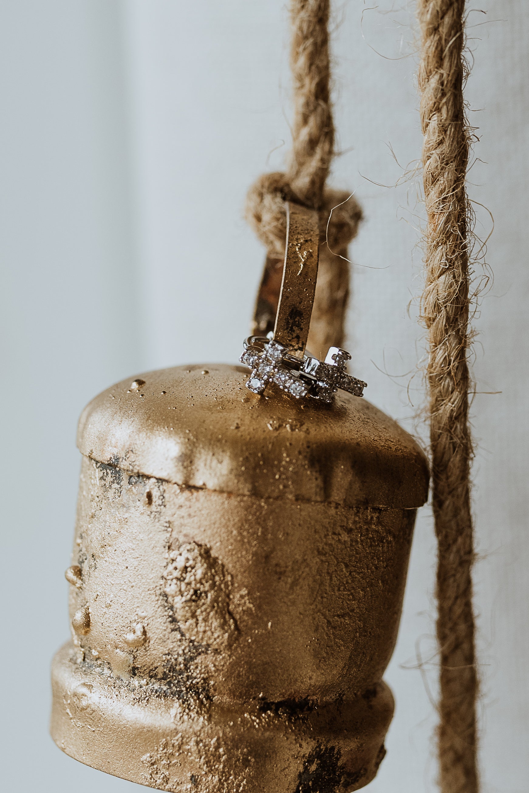 Bronze bell with a rope on a light background and earrings hanging on the bell