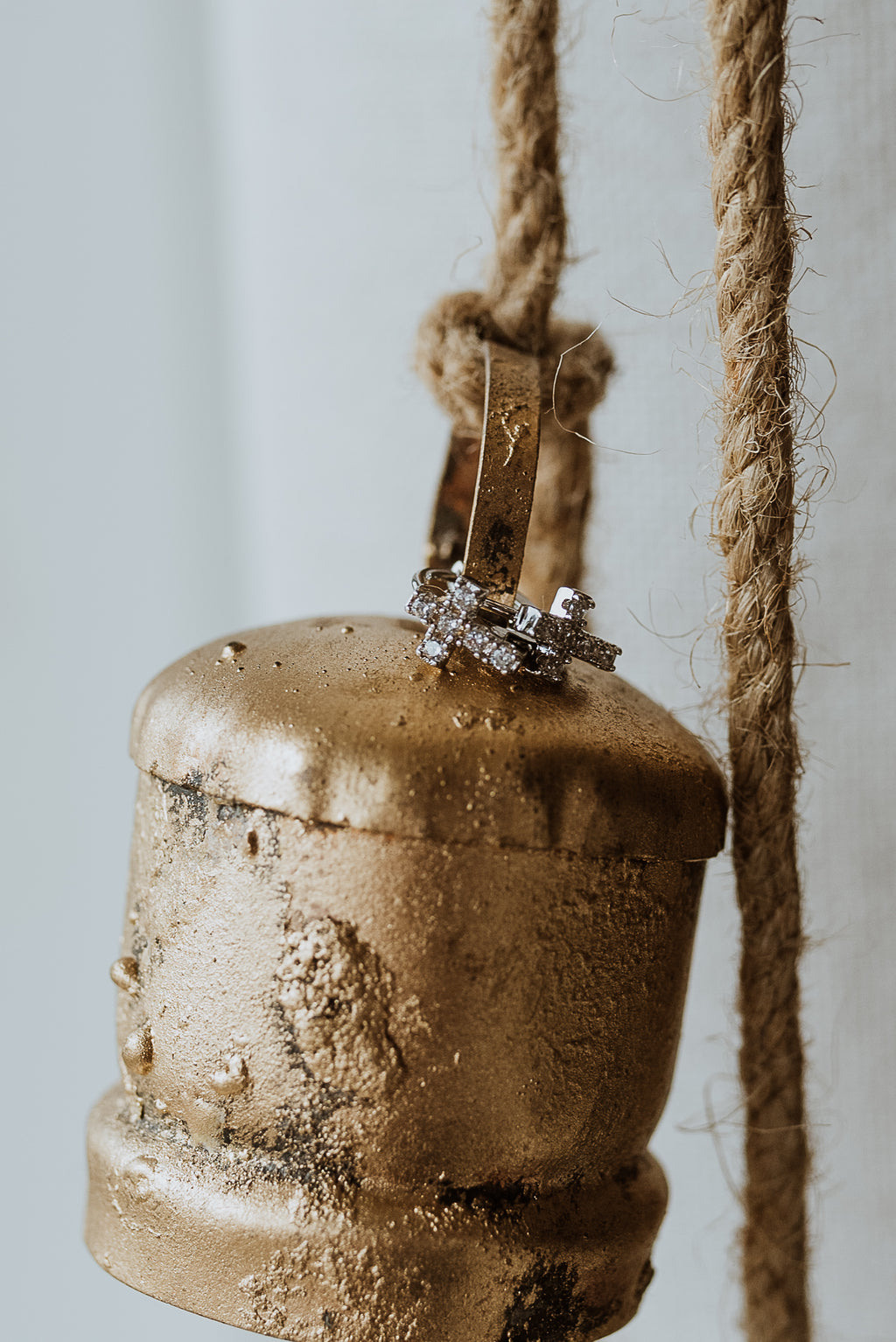 Bronze bell with a rope on a light background and earrings hanging on the bell
