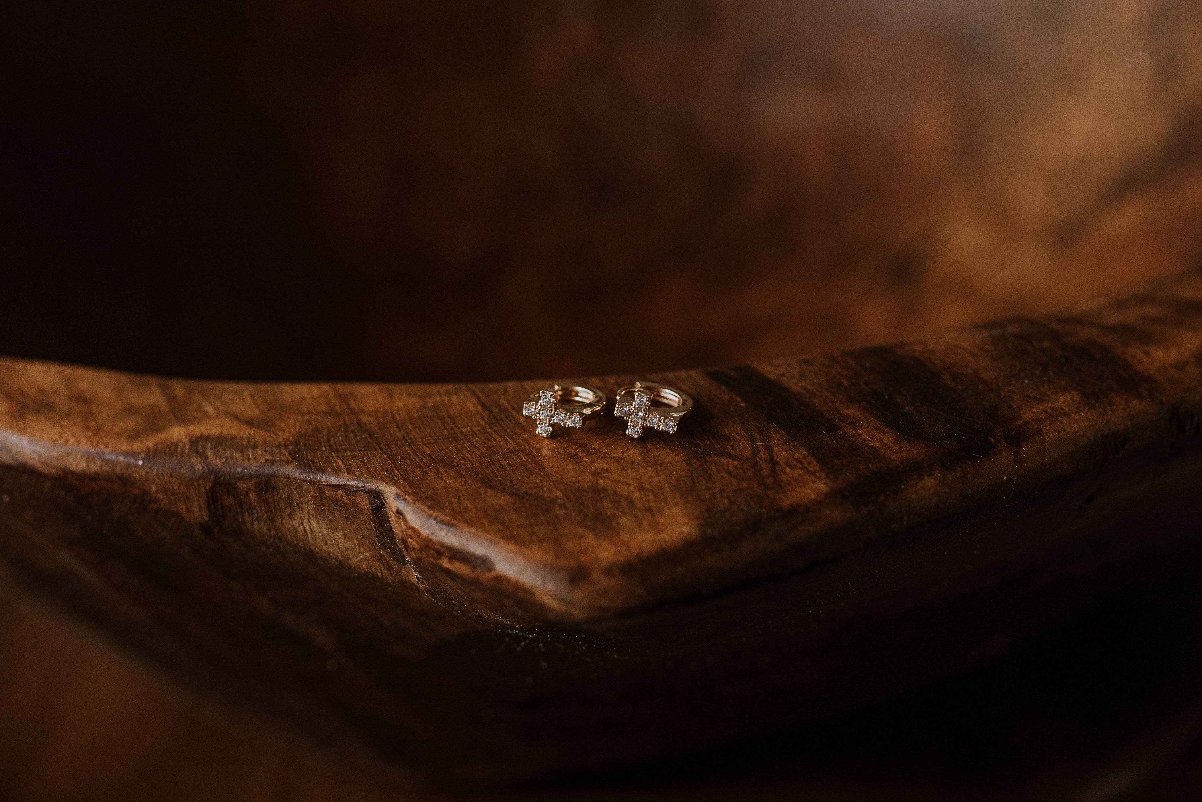 Small cross earrings on a brown textured surface