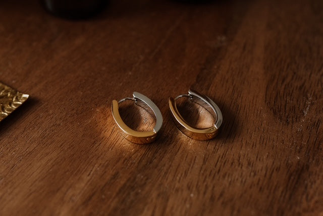 Pair of gold hoop earrings on a wooden surface